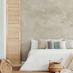 a bed with white linens and pillows in a bedroom next to a blue wall