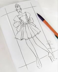 a drawing of a woman's dress on top of a paper next to a marker