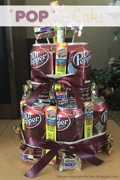 a cake made out of soda cans and wrapped in purple ribbon with the words pop on top