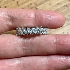 a person's hand holding an engagement ring with three stones on the top and bottom