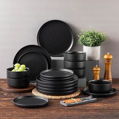 black dinnerware set on wooden table next to potted plant