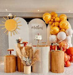 an assortment of desserts on display in front of a backdrop with balloons and sunbursts