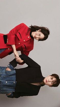 two women in black tops and red coat posing for a photo with their hands on each other's hips