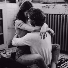 black and white photograph of two people hugging each other in front of a radiator