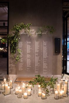 a table with candles and greenery on it in front of a sign that says wedding seating