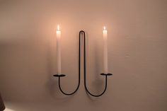 two white candles are lit on the wall next to each other, with one black candle between them