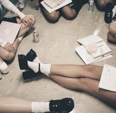 a group of people sitting on the floor with their legs crossed and reading books in front of them