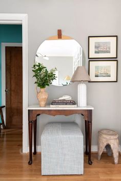 a small table with a mirror, stool and lamp on it in a living room