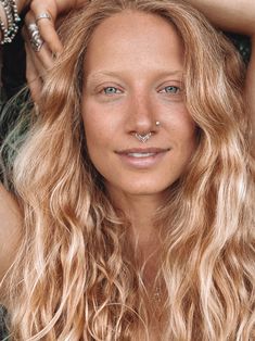 a woman with long blonde hair and piercings on her nose is posing for the camera