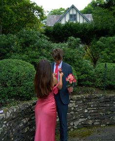 a woman in a pink dress and a man in a blue suit stand next to each other