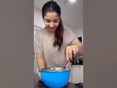 a woman is mixing something in a blue bowl