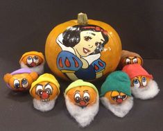 a group of stuffed animals sitting next to a pumpkin with snowmen painted on it