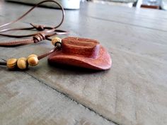 "Hand carved Cowboy Hat Necklace Pendant.  length is 16.5\" and adjustable to 10\" Carved from mahogany wood, painted with acrylic paint and finished with orange oil and beeswax.  knotted waxed polyester cord and 6 wooden beads. Since each piece is hand carved each piece may not be exactly as pictured with minor differences." Adjustable Rustic Necklace With Waxed Cord, Rustic Adjustable Necklace With Waxed Cord, Handmade Adjustable Wood Jewelry, Adjustable Artisan Natural Wood Necklace, Rustic Adjustable Wooden Bead Jewelry, Adjustable Brown Necklace With Waxed Cord, Adjustable Brown Waxed Cord Necklace, Artisan Necklace With Adjustable Waxed Cord, Casual Adjustable Brown Necklace