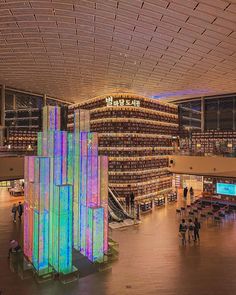 the interior of a large building with many bookshelves and people walking around it