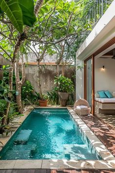 an outdoor swimming pool in the middle of a house with trees and plants around it