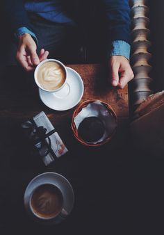 a person sitting at a table with two cups of coffee