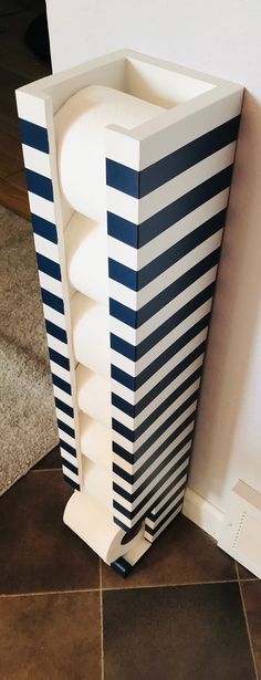 a tall white and blue vase sitting on top of a tile floor