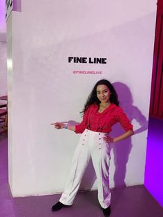 a woman standing in front of a white wall with the words fine line on it