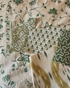 several different patterns and sizes of fabric on a bed sheet with green flowers in the background