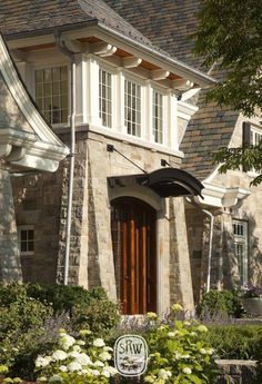 the front entrance to a house with flowers and shrubs