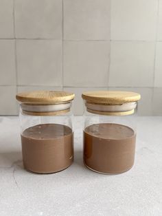 two jars filled with brown liquid sitting on top of a counter