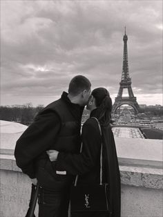 a man and woman standing next to each other in front of the eiffel tower