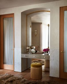 a dressing table with stool and mirror in a room next to a door that leads to another room