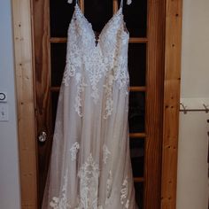 wedding dress hanging in front of wooden door