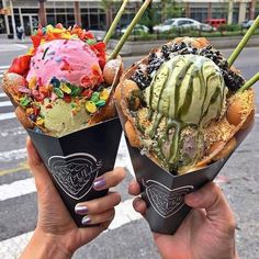 two people holding up ice cream cones in their hands