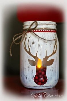 a mason jar with a deer's head painted on it and some raspberries in the bottom