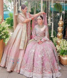 two women dressed in pink and gold sitting next to each other