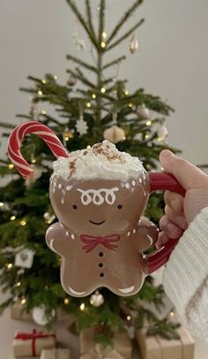 a person holding up a christmas ornament in front of a tree with candy canes