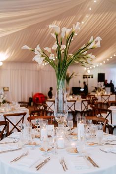 a vase filled with white flowers sitting on top of a table covered in tables cloths