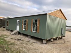 two tiny houses sitting in the middle of a dirt lot with windows on each side