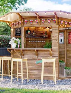 a small wooden bar with three stools in front of it and an umbrella over the bar