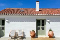 two wooden chairs sitting in front of a white building