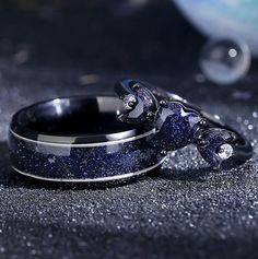 two wedding rings with blue and silver glitters on the surface, one is shaped like a turtle