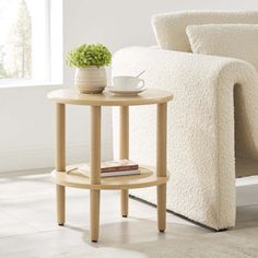 a small table with a cup on it next to a white couch and chair in a living room