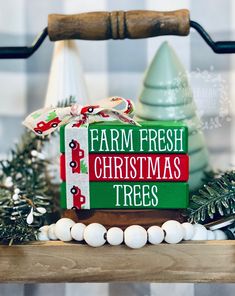 a sign that says farm fresh christmas trees on top of a wooden table with ornaments around it