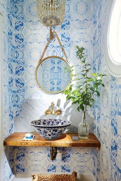 a white sink sitting under a mirror next to a wooden shelf with a potted plant on it