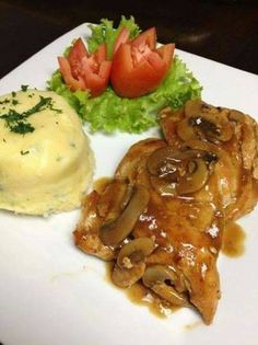 a white plate topped with meat covered in mushroom gravy and mashed potatoes