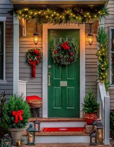 a green door with christmas wreaths and lights on the front porch, surrounded by greenery