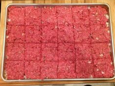 raw ground beef in a baking pan on a wooden counter top with a person standing next to it