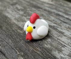 a close up of a small toy chicken on a wooden surface with one eye open