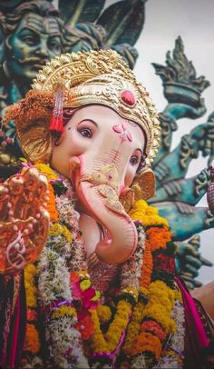 an elephant statue is adorned with flowers and garlands in front of a large sculpture