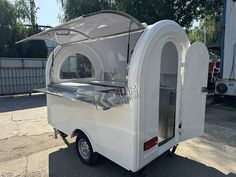 an outdoor food cart parked in front of a building with the door open and windows closed