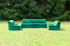 a group of green couches sitting on top of a lush green grass covered field