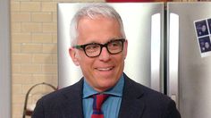 an older man wearing glasses and a red tie in front of a refrigerator with magnets on it