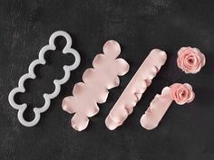 three cookie cutters, one with pink roses and the other with white frosting