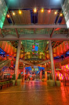 the inside of a building with lights on and plants in large planters at the bottom